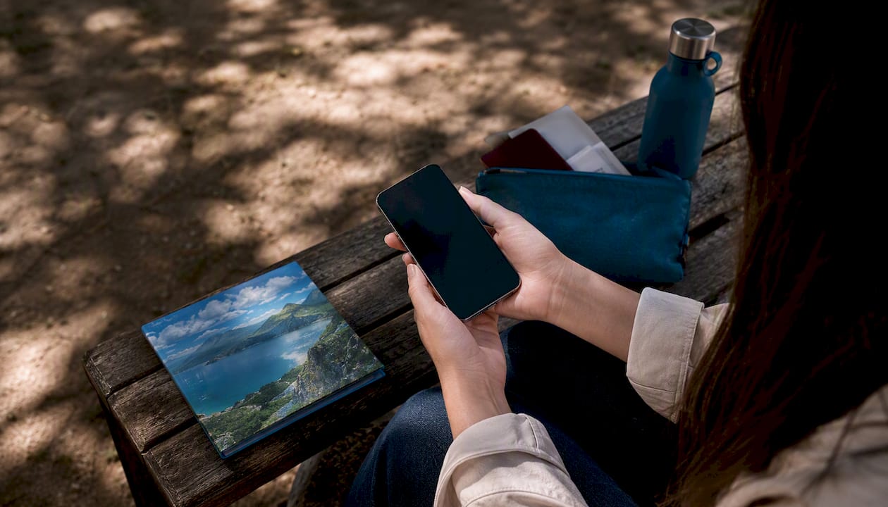 Hands activating eSIM on smartphone at travel table